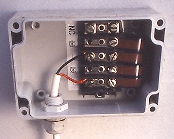 inside of junction box with flat DC-cables from solar panel (right) and connections to OK4E inverter (red and black wires). Bypass diodes not visible under flat cables.
